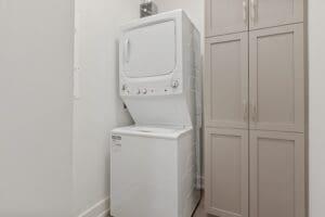 Washer and dryer in a room next to a gray cupboard