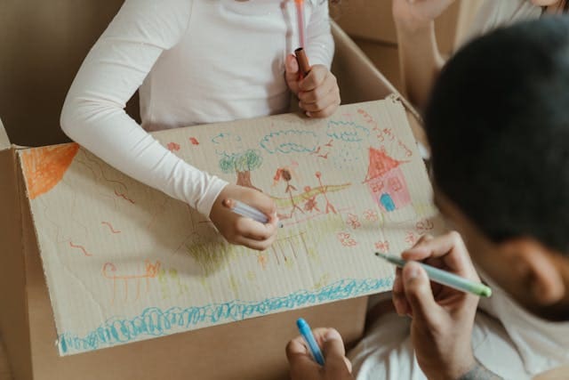 Picture of a parent and kid drawing on a cardboard box